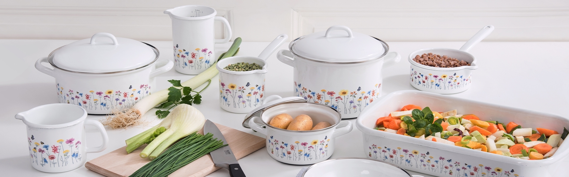 Weißes Emaille-Kochgeschirr mit Blumenmuster in Küche